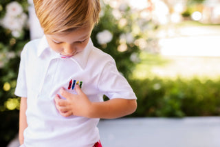 Child holding colorful crayons outdoors with a blurred natural background
