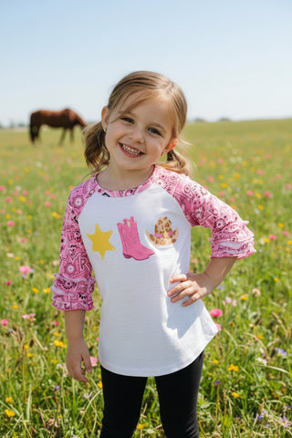 A children's raglan-style top displayed on a dress form. The shirt has a light gray body, pink patterned three-quarter sleeves, and a front graphic with a yellow star, pink cowboy boots, and a yellow/orange sun.