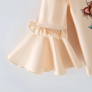 Close-up of a light cream or pale peach satin garment with a ruffled cuff and a partial cartoon-style printed character on the sleeve, shown against a plain light background.