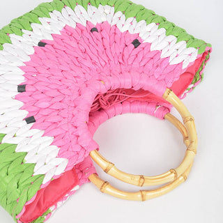 Colorful woven bag with pink, green, and white pattern and bamboo handle on a white background
