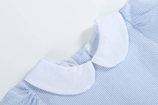 Close-up of a blue and white striped garment with a white collar on a light gray background