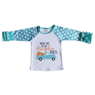 Children's long-sleeve shirt with polka dot sleeves and pumpkin patch design on a beige carpet.