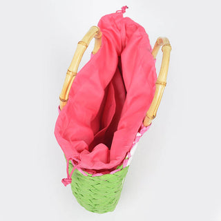 Pink drawstring bag inside a green wicker basket on a white background
