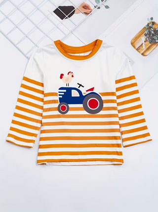 A children's long-sleeve top laid flat on a white surface. The shirt has a white upper chest and collar, orange trim, orange-and-white horizontal stripes on the sleeves and lower body, and a central tractor graphic with a small rooster illustration.