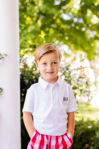 Young boy wearing a white polo shirt with a logo outdoors
