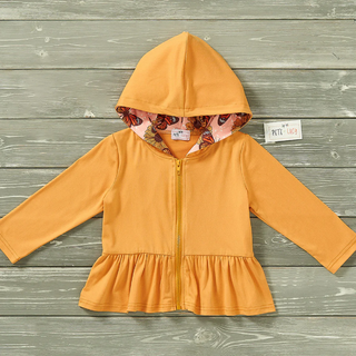 Yellow hoodie with floral lining on a wooden surface