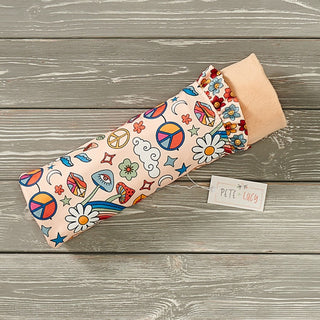 A multicolored blanket with a bohemian design, featuring floral patterns and the brand name 'Pete + Lucy' tagged on it, placed on a wooden surface.