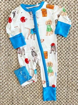 Baby onesie with dog pattern and blue trim on a textured surface